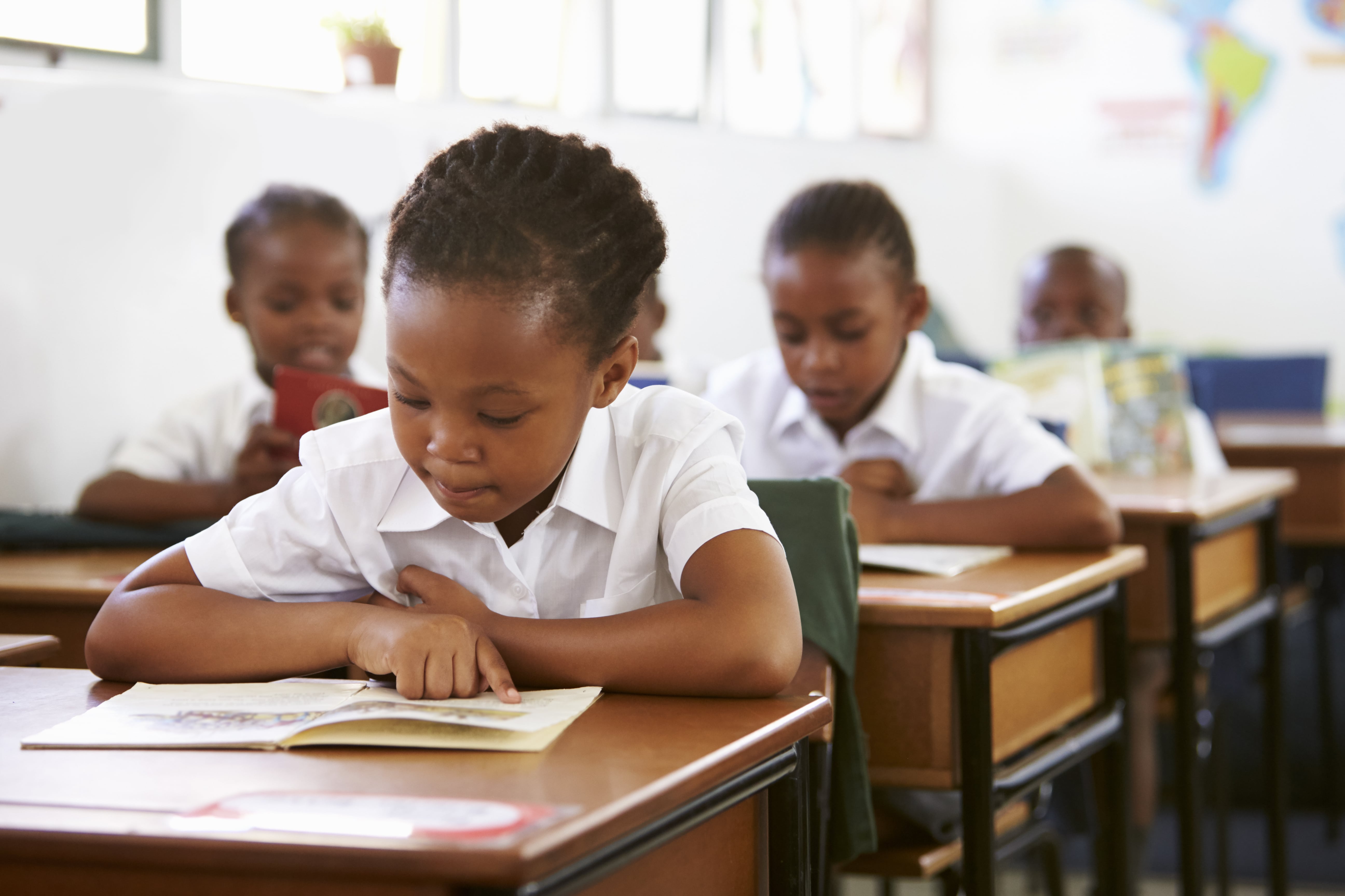 schoolgirl-reading-at-her-desk-in-elementary-PPHUQY8-min